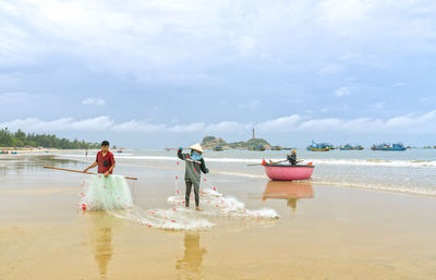 People standing on beach against sky