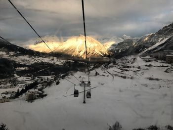 Ski lift over snowcapped mountains against sky