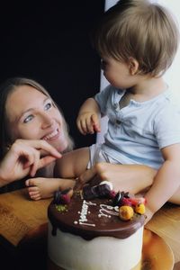 Portrait of blonde cute boy with mother eating cake at his birthday