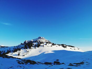 Scenic view of snowcapped mountains against blue sky