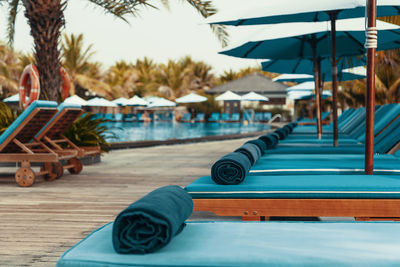 Lounge chairs by swimming pool at beach against blue sky