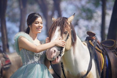 Portrait of a beautiful woman with a horse in the forest background.