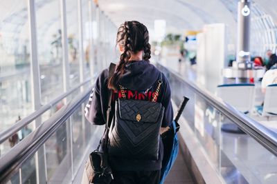 Rear view of woman standing on escalator