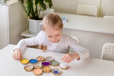 A girl student sits at a desk in the classroom and collects figures / puzzles / small toys 