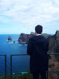 Rear view of man looking at sea against sky