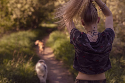 Rear view of young woman standing on footpath at park