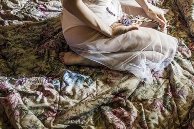 Low section of woman resting on bed