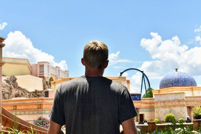 Rear view of man looking at buildings against sky