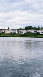 Scenic view of river by buildings against sky