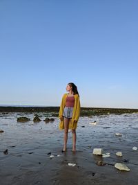 Full length of woman standing on beach against clear sky