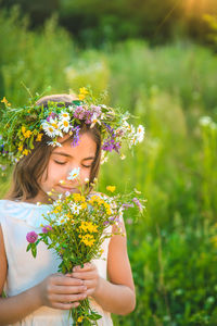 Smiling girl wearing floral crown smelling flower