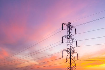 Low angle view of electricity pylon against sky during sunset