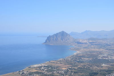 Scenic view of sea and mountains against clear blue sky