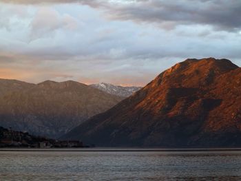 Scenic view of sea by mountains against sky