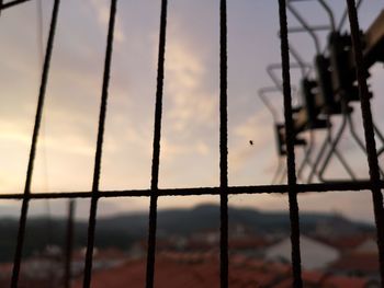 Close-up of metal fence against sky during sunset