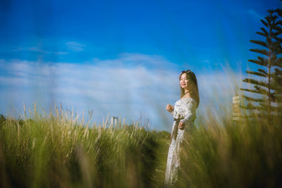 Side view of woman standing on field against sky