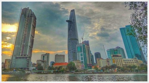 City at waterfront against cloudy sky