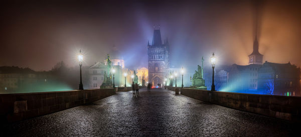 Illuminated city buildings by river at night