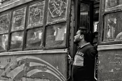 Side view of man standing against building