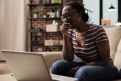 Young woman using phone while sitting at cafe