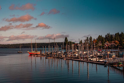 Boats moored at harbor against sky during sunset