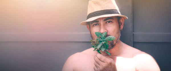 Portrait of man wearing hat standing against wall