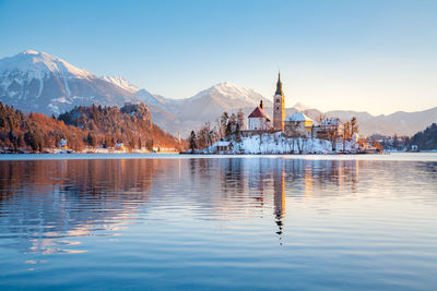 Scenic view of lake by buildings against sky during winter