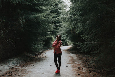 Young woman standing on pathway amidst trees