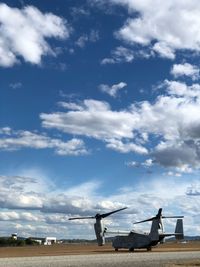 Aircraft on land against cloudy sky 