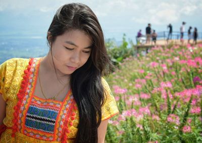 Close-up of beautiful woman standing by flowers