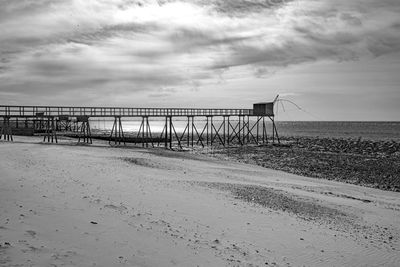 Pier on beach against sky