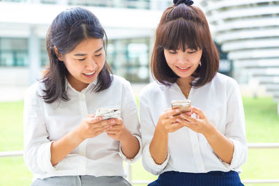 Happy young woman holding smart phone outdoors