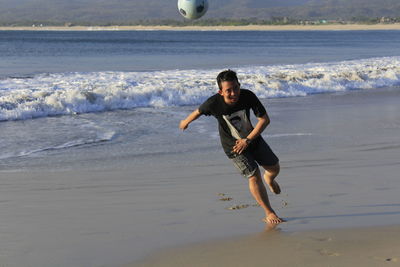 Full length of man playing with ball on beach