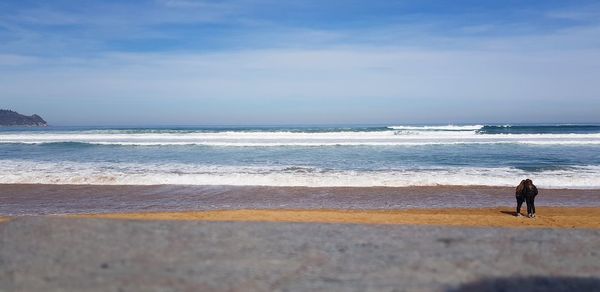 Rear view of people on beach against sky