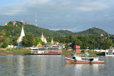 Boat on river by trees against sky