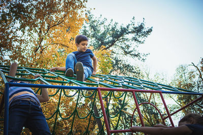 Low angle view of siblings playing on outdoor play equipment