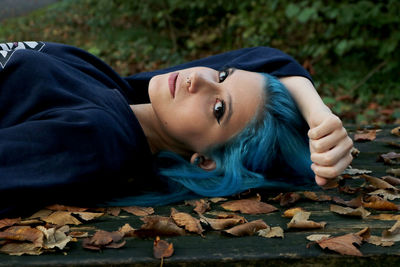 Portrait of young woman lying on bench during autumn