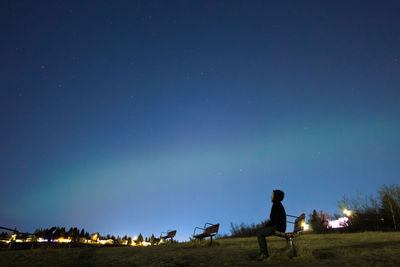 Rear view of man walking on field against sky at night