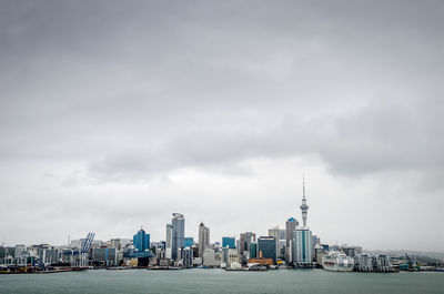 City at waterfront against cloudy sky