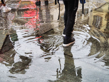 Low section of man standing on puddle