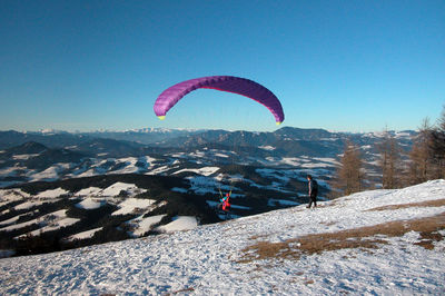 People paragliding over mountain against sky