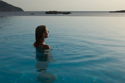 High angle view of woman in infinity pool against sea