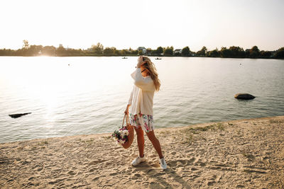 Woman standing at beach against sky