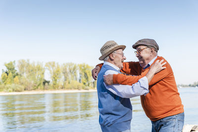 Two old friends reuniting at the riverside, embracing each other happily