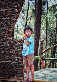 Portrait of boy standing against tree