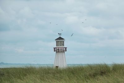 Lighthouse on beach against sky