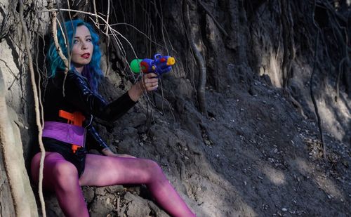 Portrait of woman holding squirt gun while sitting on field