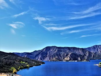 Scenic view of sea and mountains against blue sky