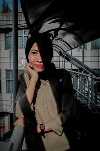 Portrait of smiling young woman standing against built structure