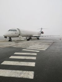 Airplane on airport runway against sky
